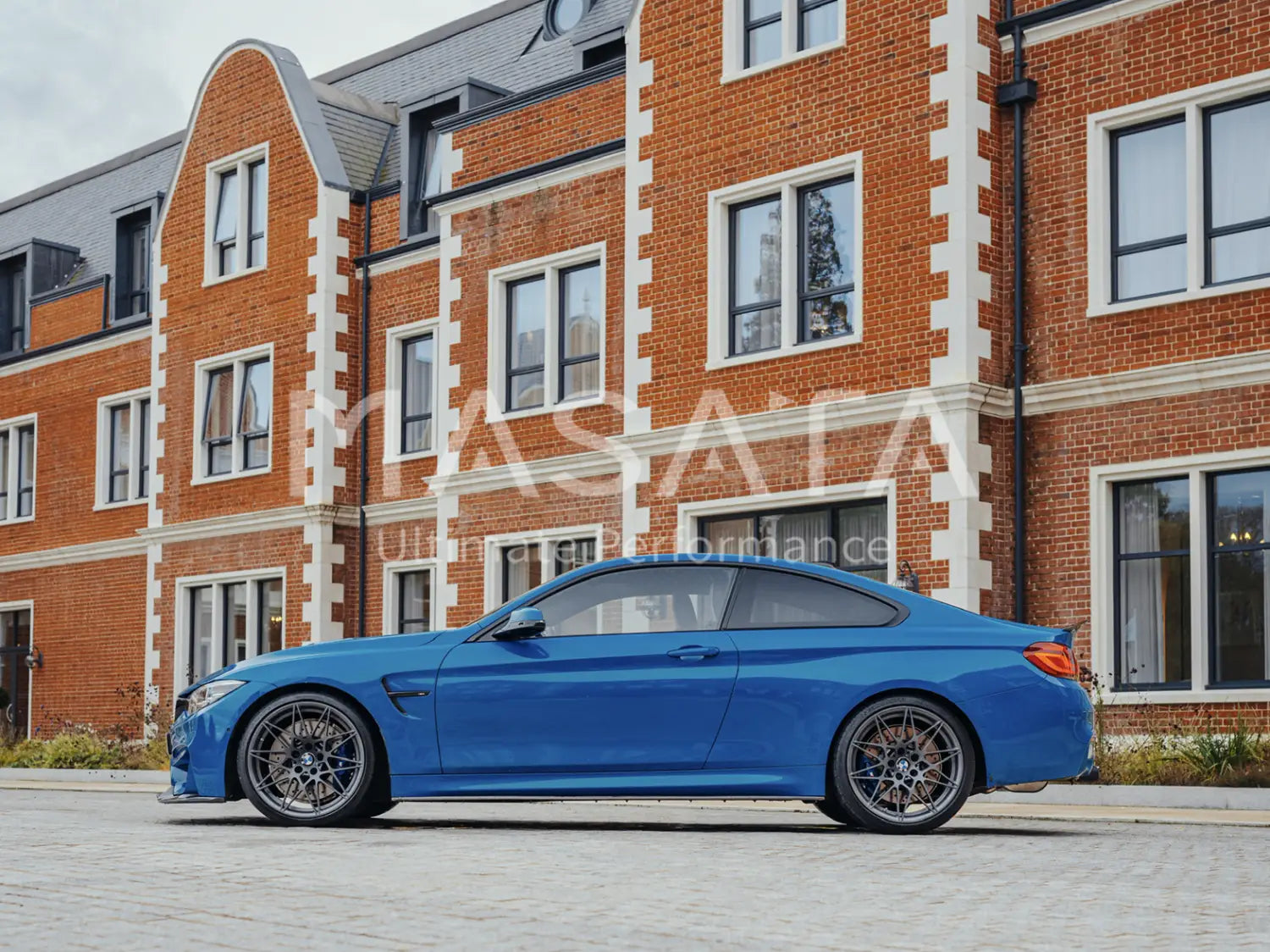 Bright blue BMW M4 coupe with dark alloy wheels showcasing Masata BMW F80 performance lowering springs.